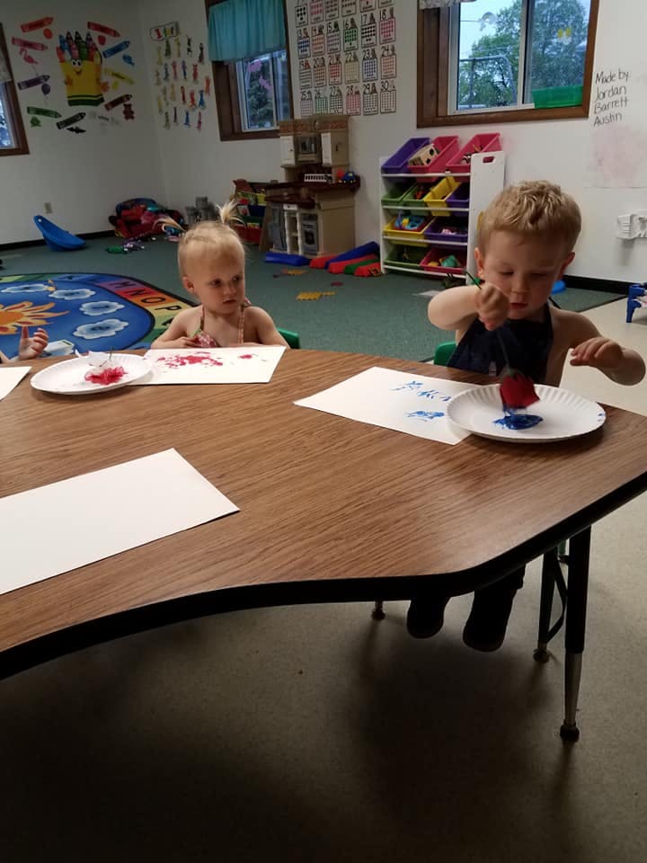 Two children painting at a table in a classroom