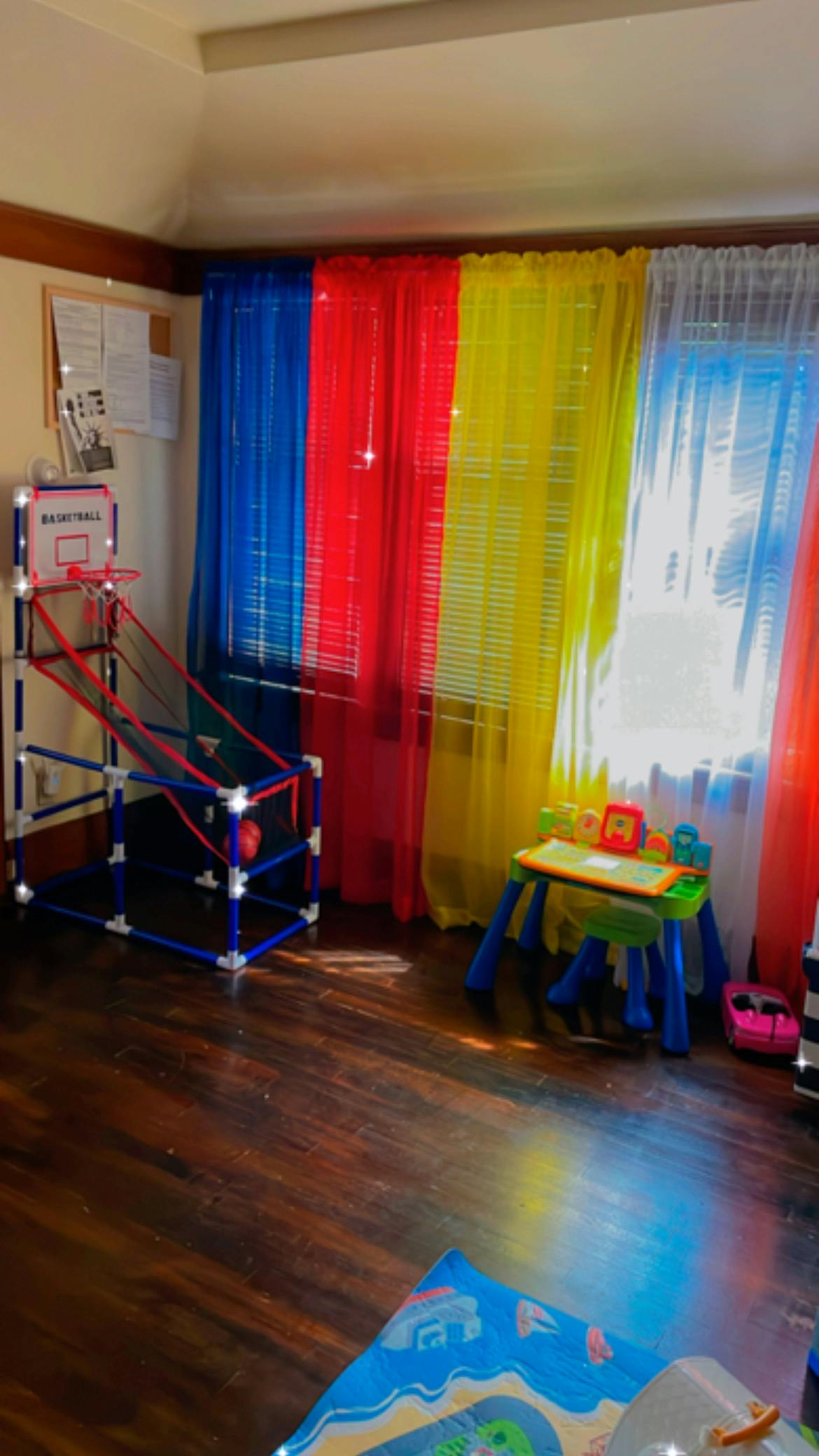 Indoor basketball hoop and small activity table in a room with colorful curtains