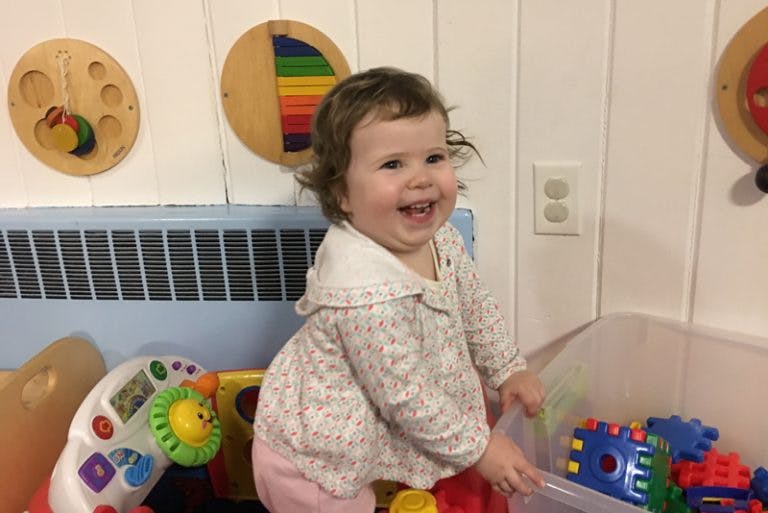 Child standing next to a bin of toys