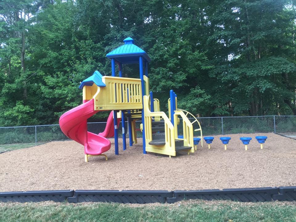 Playground with yellow and blue structure, red slide, and blue stepping pods