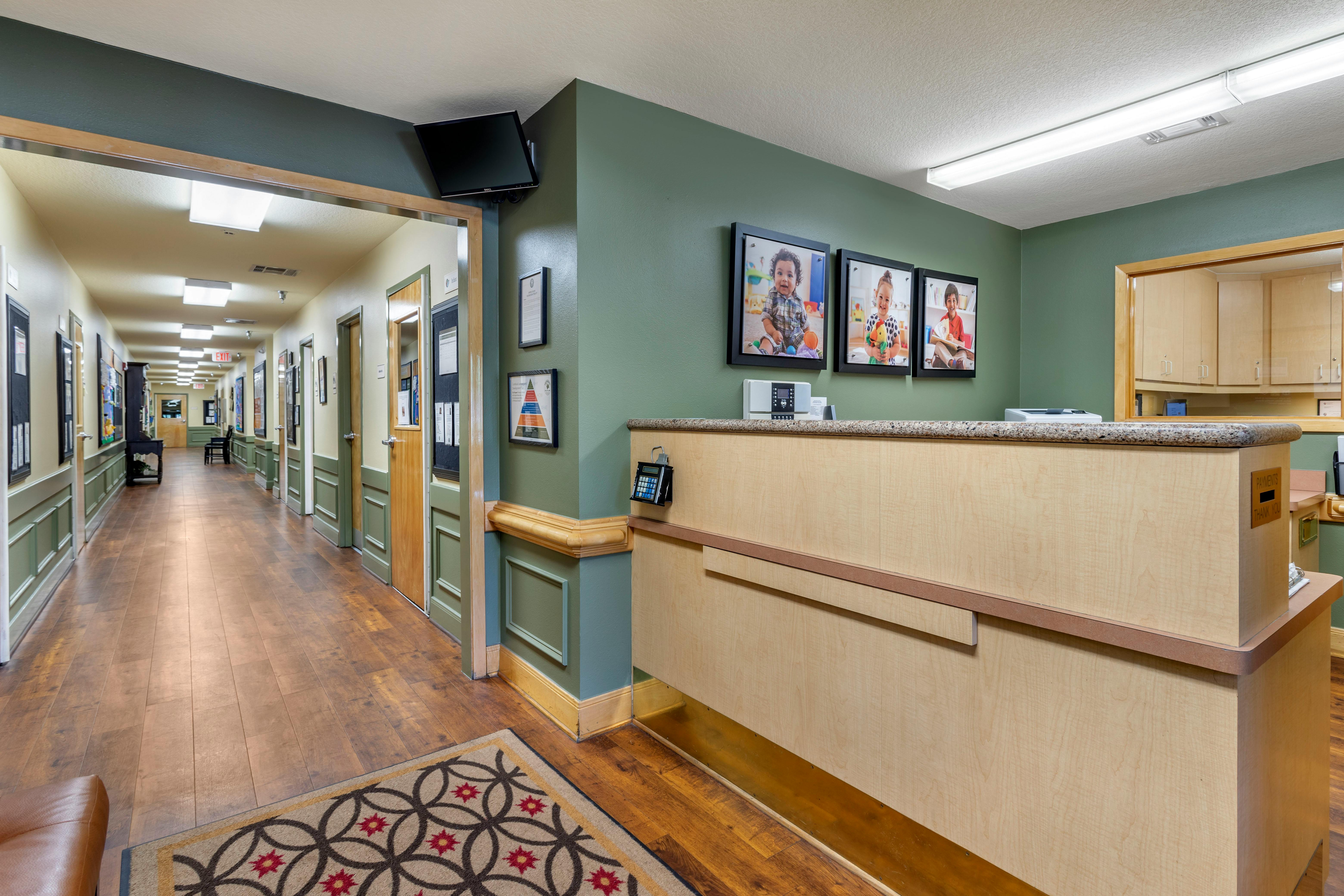 Reception desk with three framed images of children and a long hallway