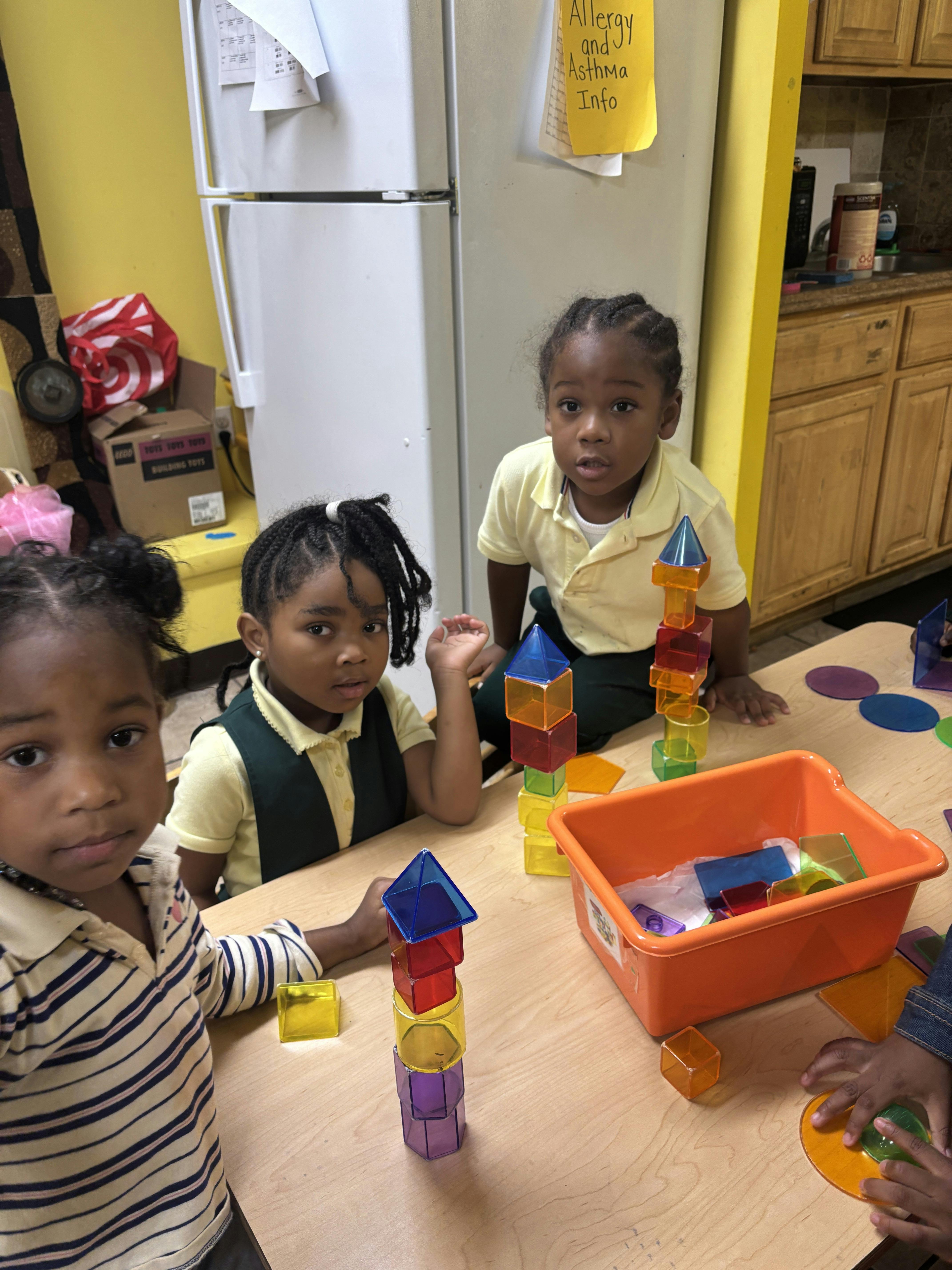 Three children playing with colorful building blocks at a table