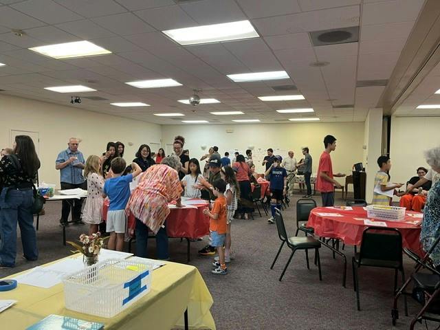 People gathered in a large room with tables for a community or social event