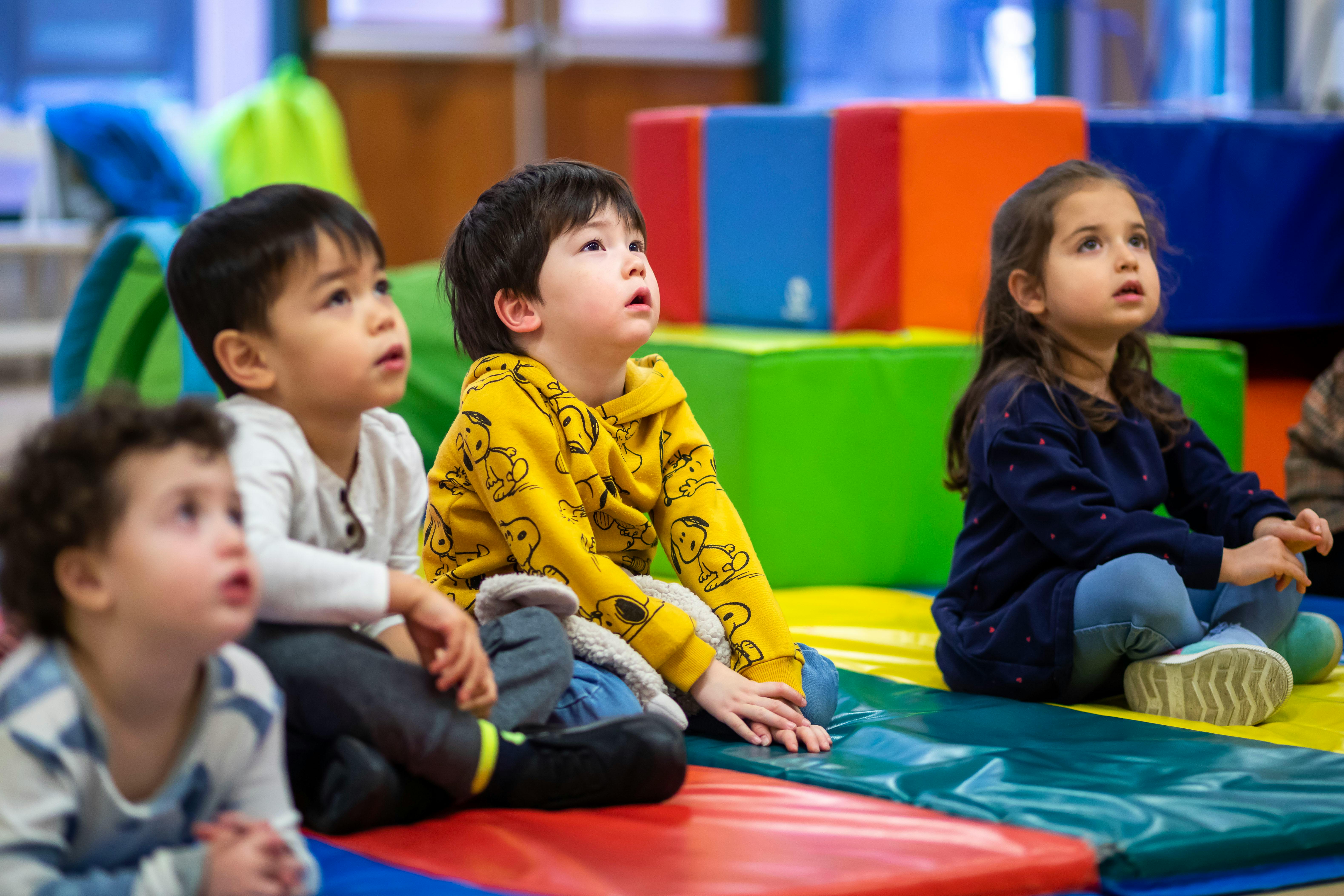 Four children sitting on mats looking up