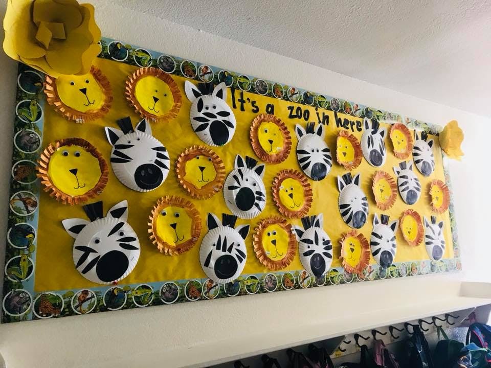 Bulletin board with paper plate lions and zebras, text says "It's a zoo in here"