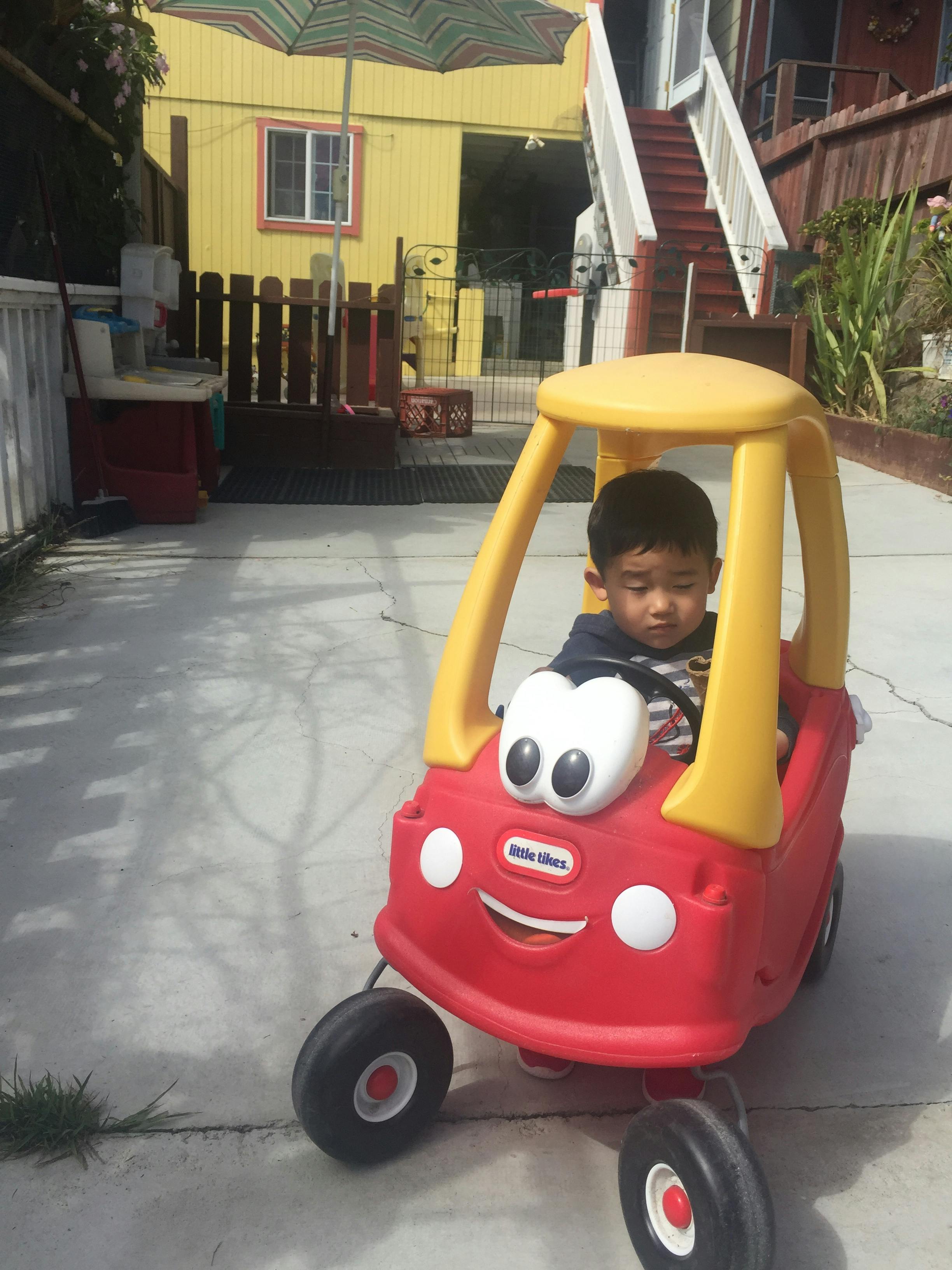 Child in a red toy car