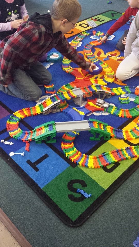 Child playing with a colorful toy car track on a rug