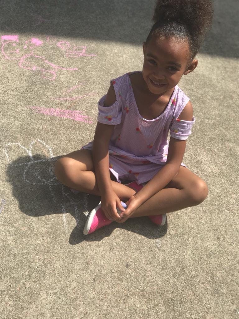 Child sitting cross-legged on pavement