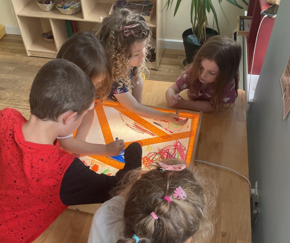 Children drawing on a light table