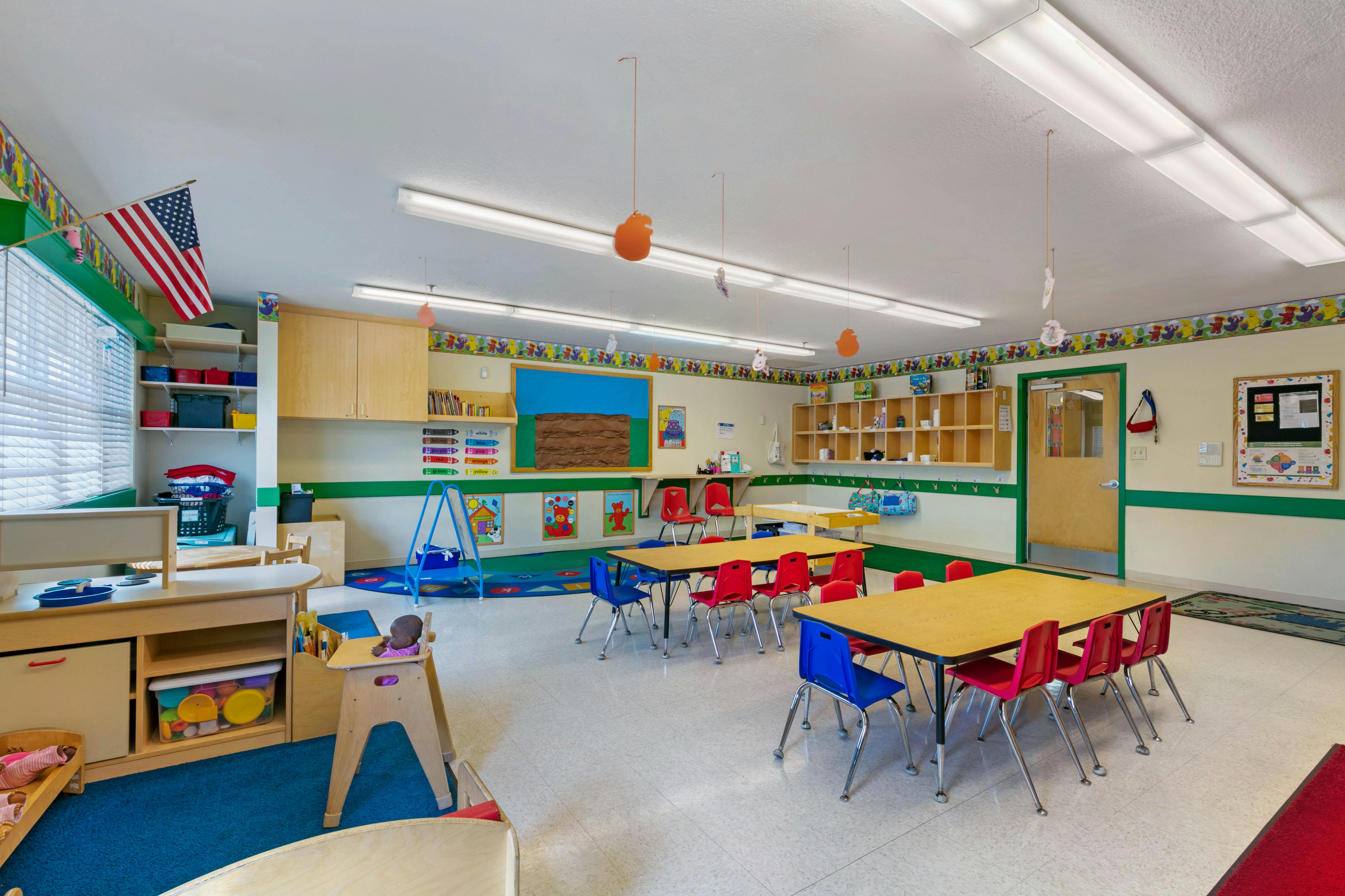 Classroom with tables, chairs, a crib, and a doll in a high chair