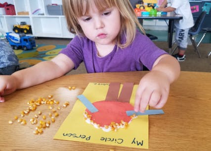 Child making a craft with paper and corn kernels