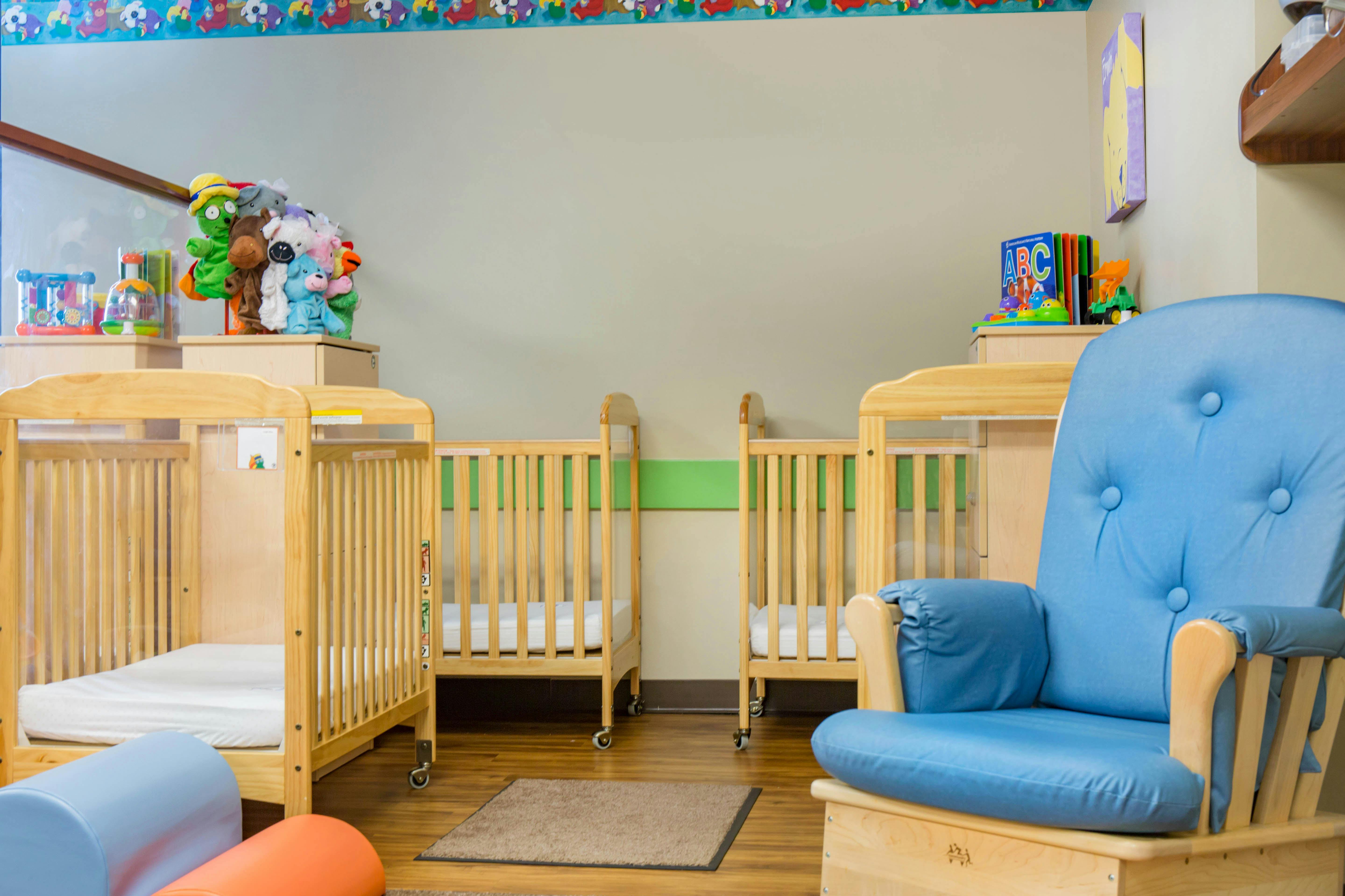 Cribs and a blue rocking chair in a nursery room