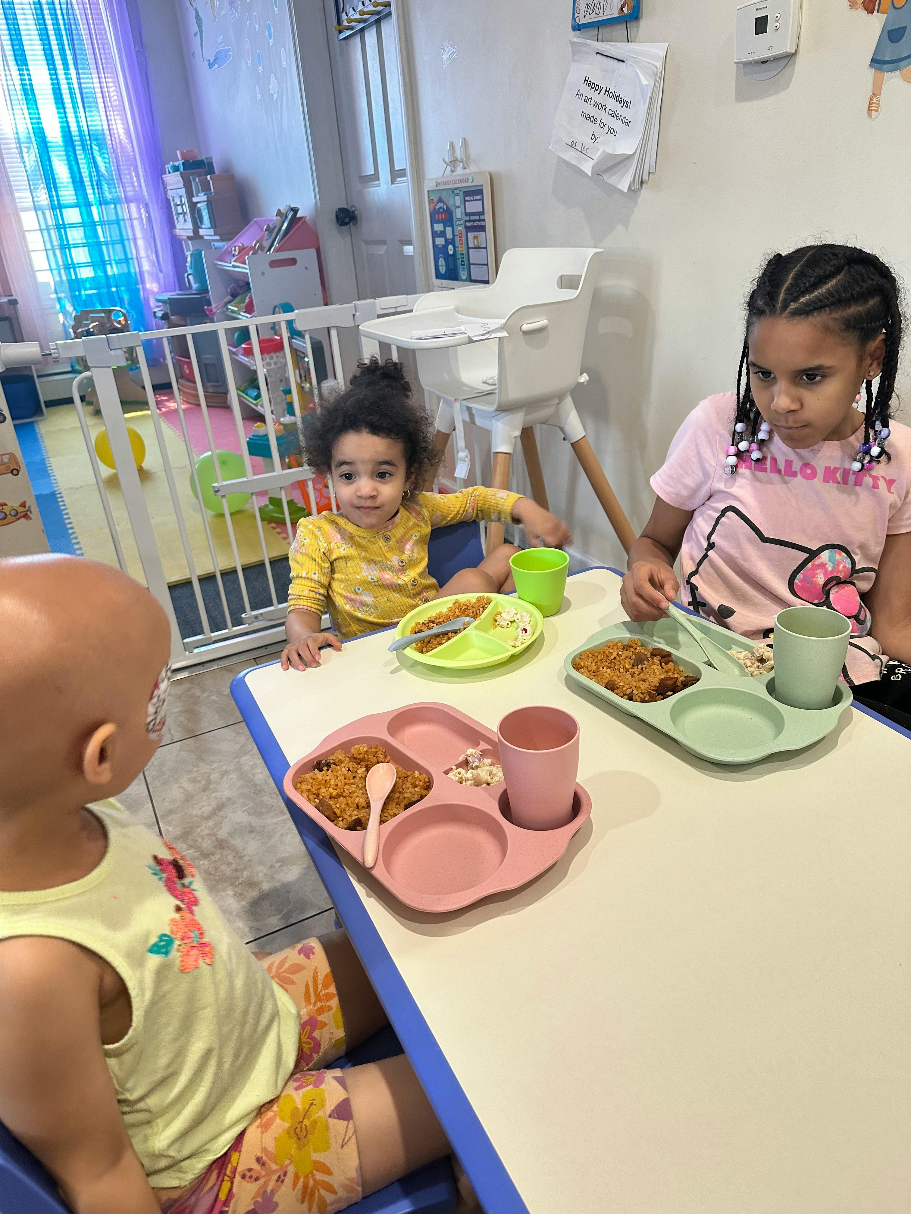 Three children sitting at a table with plates of food