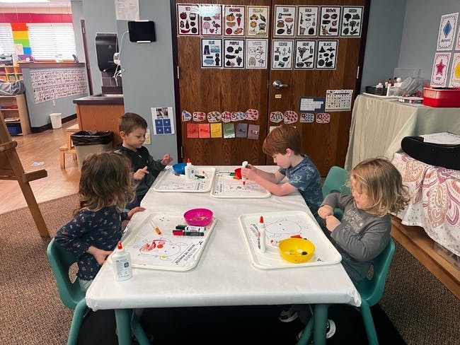 Four children sitting at a table doing crafts