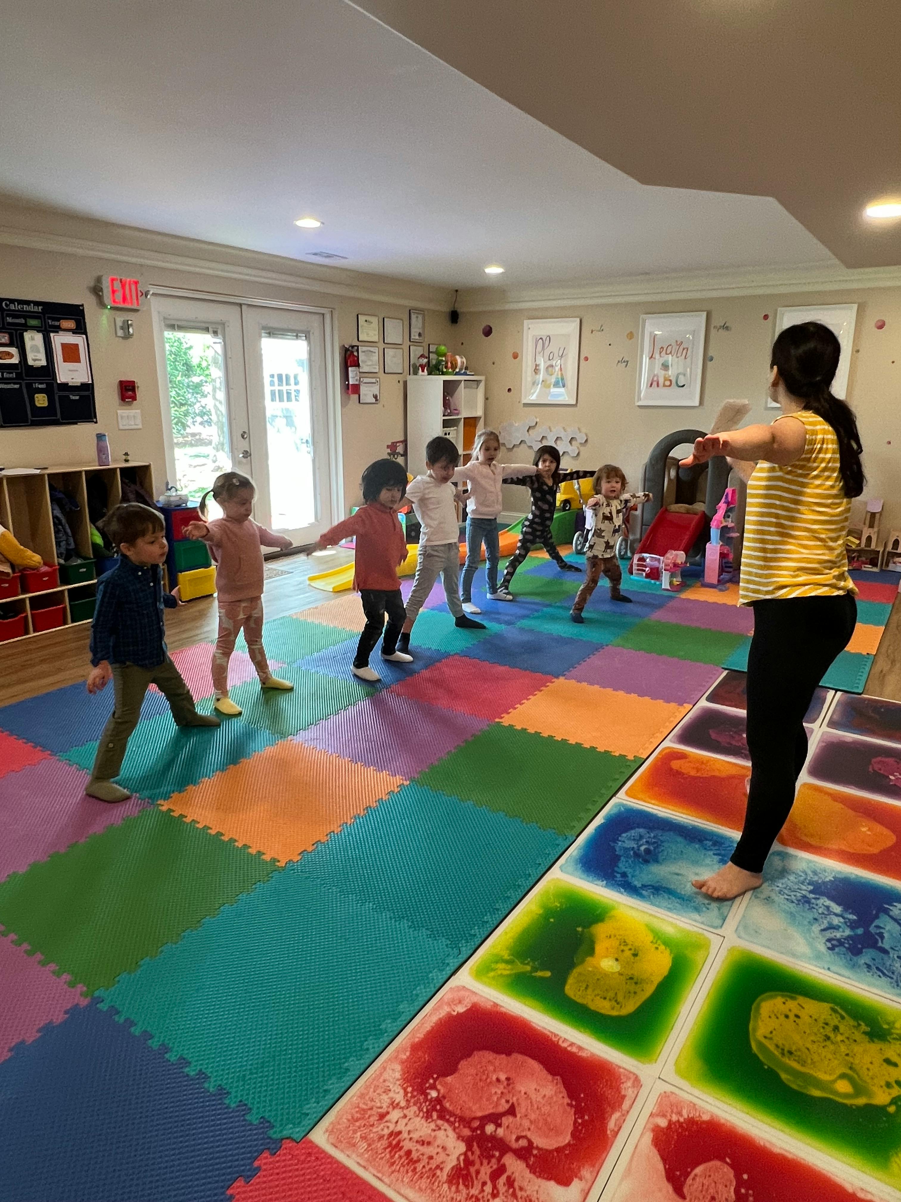 Adult and children exercising in a room with colorful floor mats