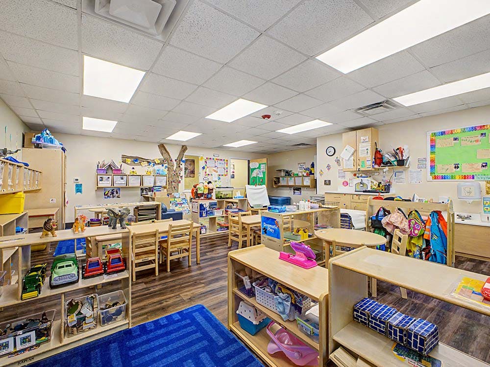 Classroom filled with child-sized tables, chairs, and shelves of toys