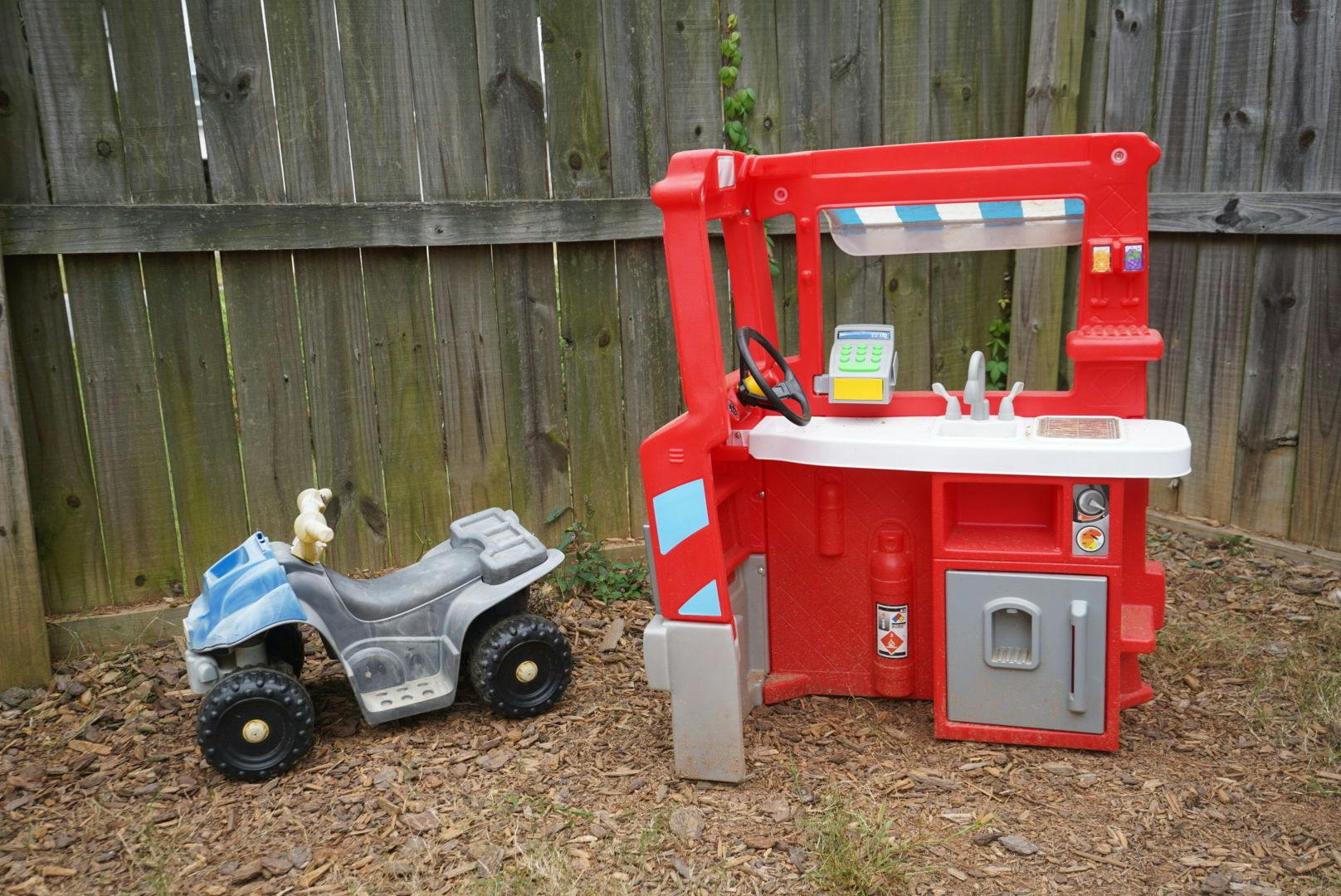 Toy ATV and red play kitchen set outdoors