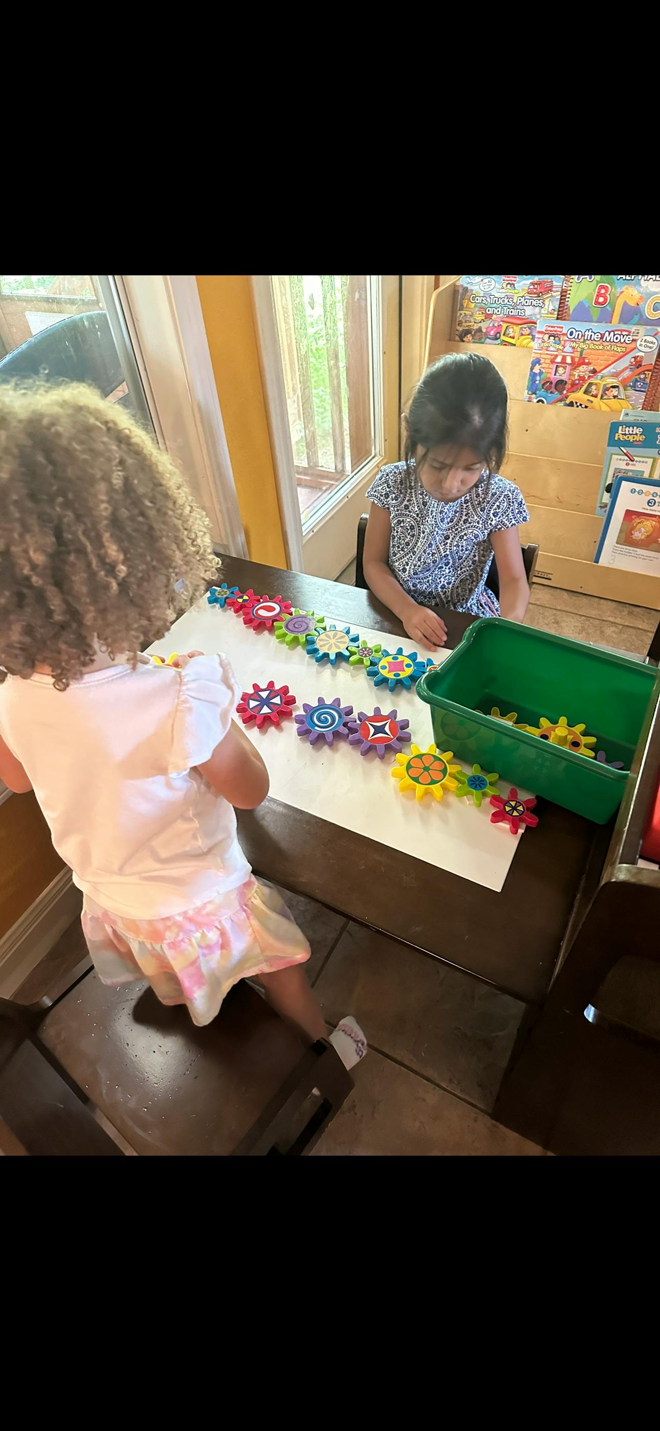 Two children playing with colorful interlocking gears on a table