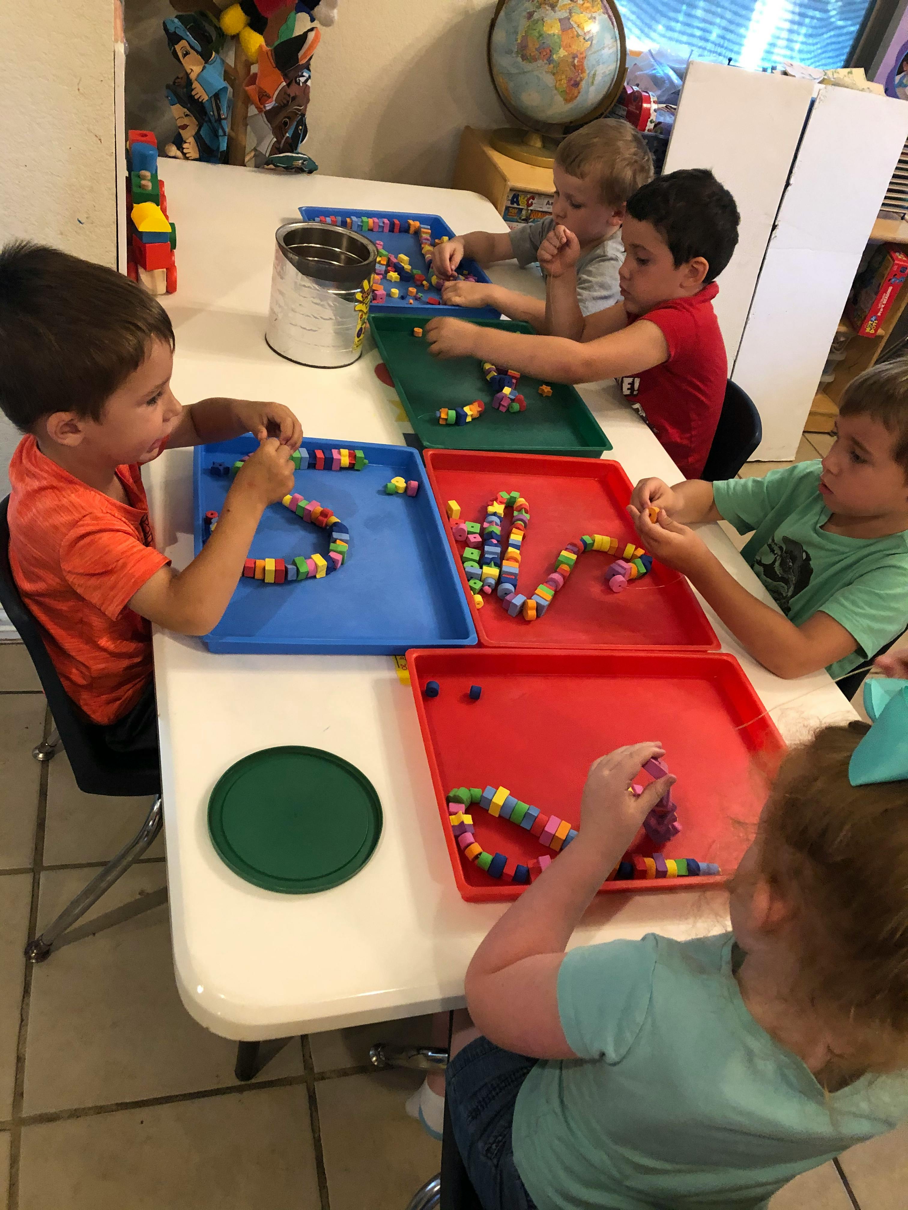 Children at a table playing with colorful interlocking toys in a classroom