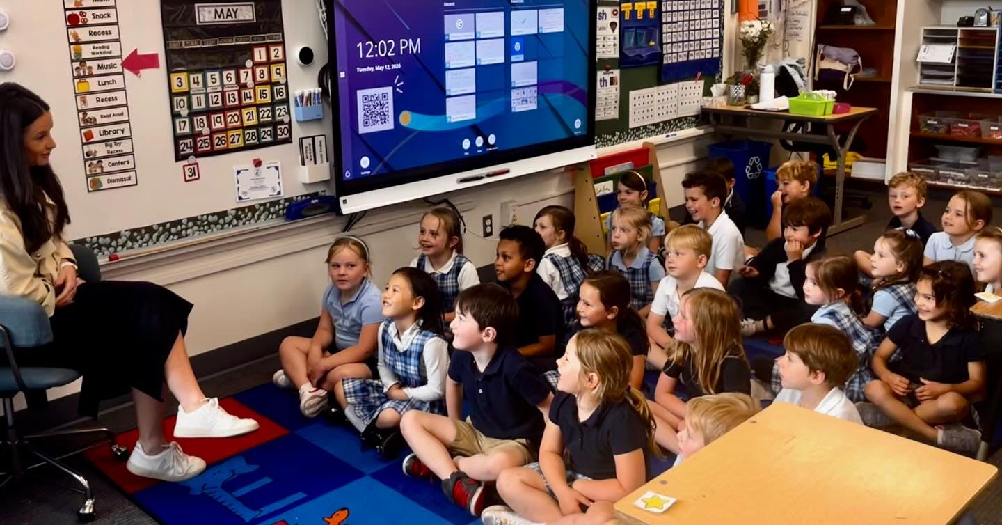 Adult person reading to a group of children in a classroom