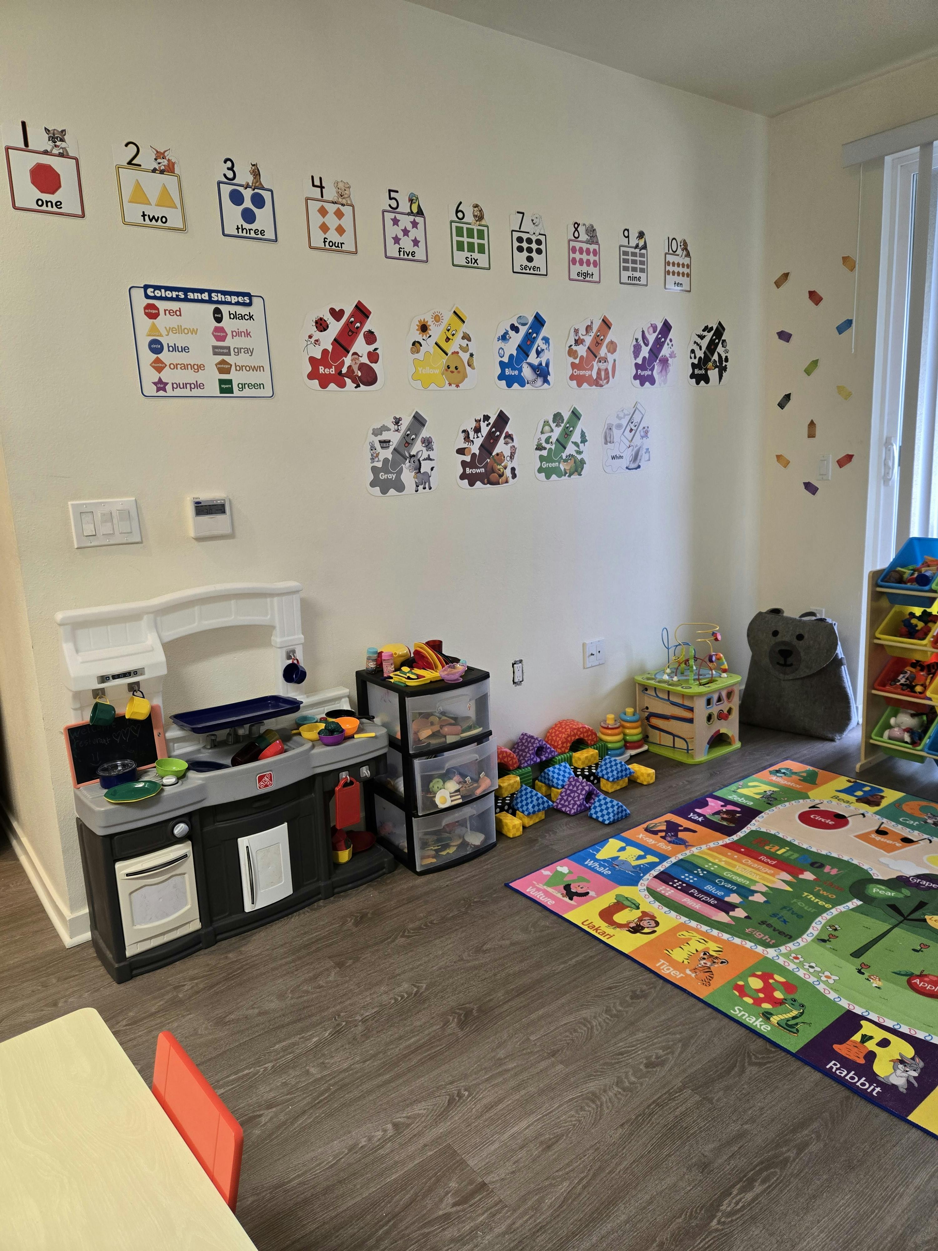 Playroom with toy kitchen, storage, colorful rug, and wall decorations