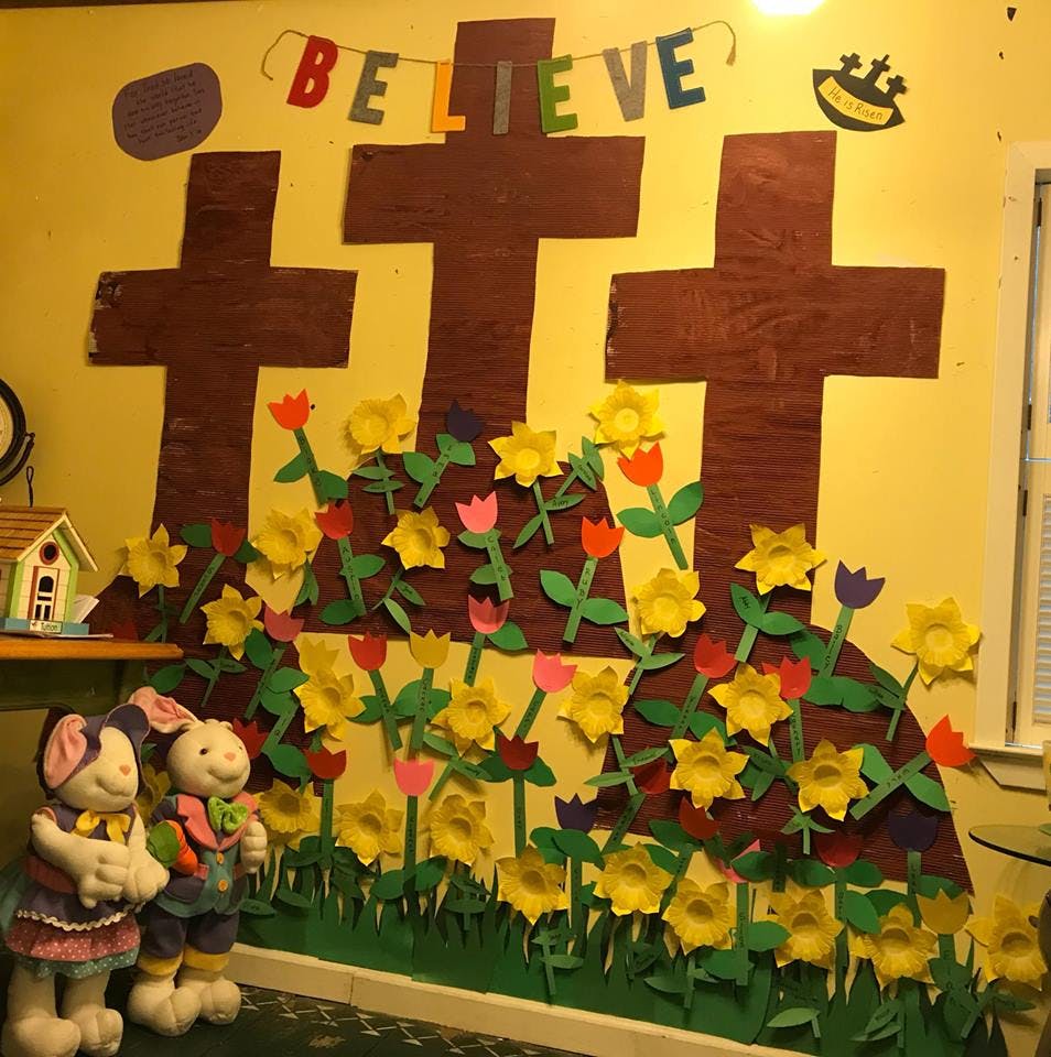 Wall decoration with three crosses, flowers, and a "BELIEVE" banner