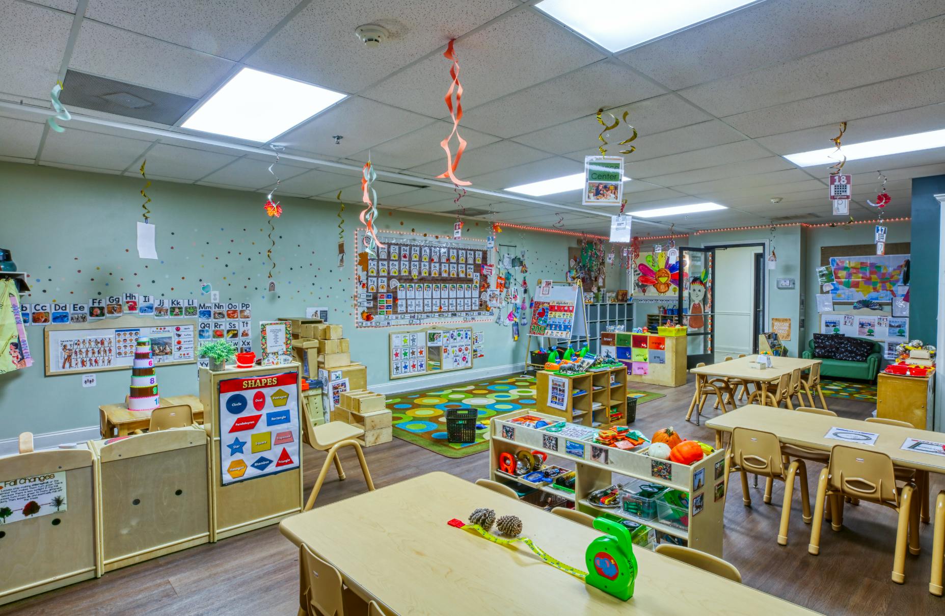 Classroom with small tables and chairs, ABCs, numbers, and shapes on walls