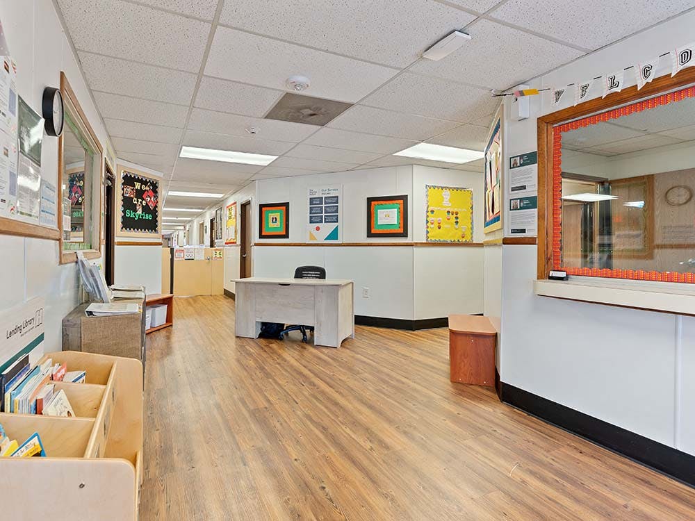Hallway with a wooden floor and white walls, decorated with bulletin boards