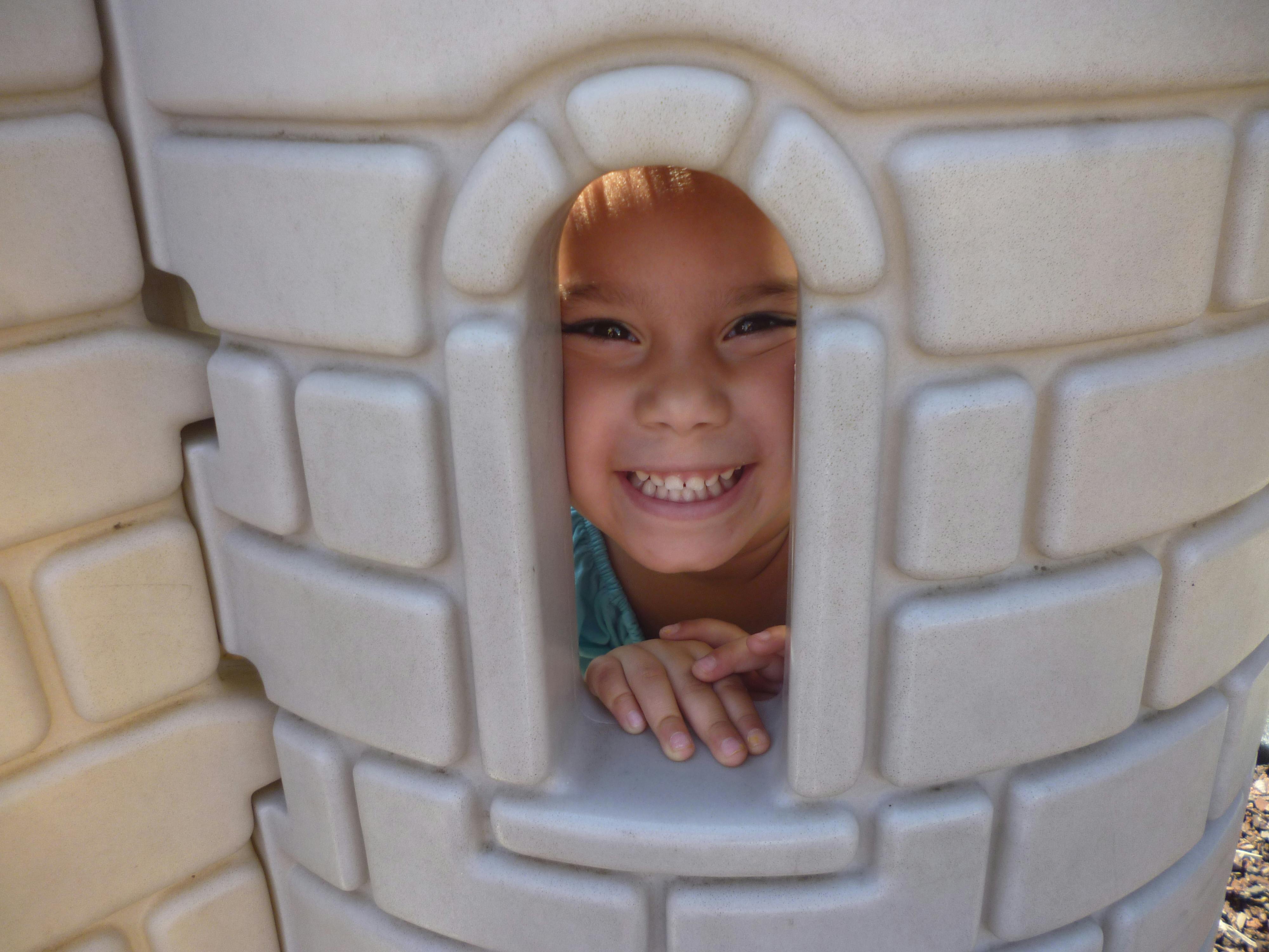Child looking through a window in a playhouse