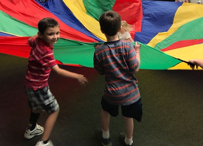 Two children holding a colorful parachute
