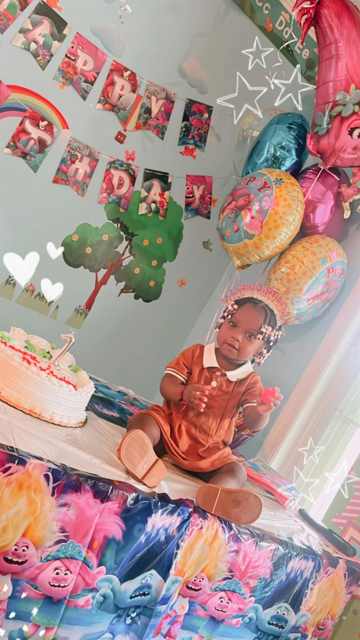 Child sitting at a table with a birthday cake and balloons