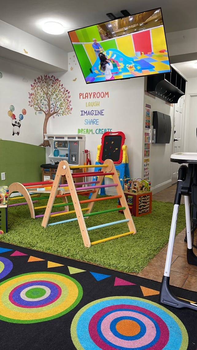 Indoor playroom with climbing structure, play kitchen, and wall decor
