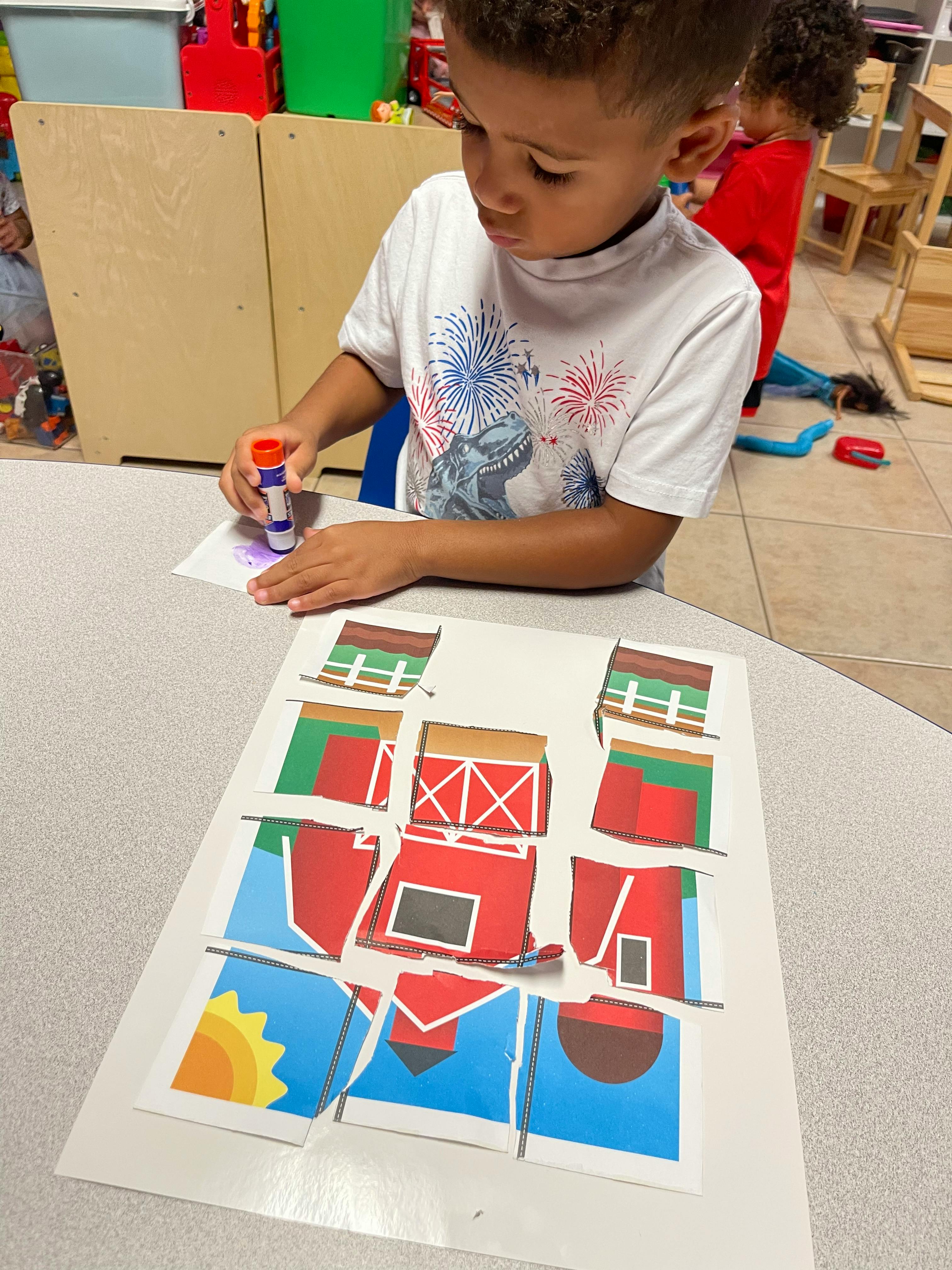 Child using a glue stick on paper with a barn-themed craft