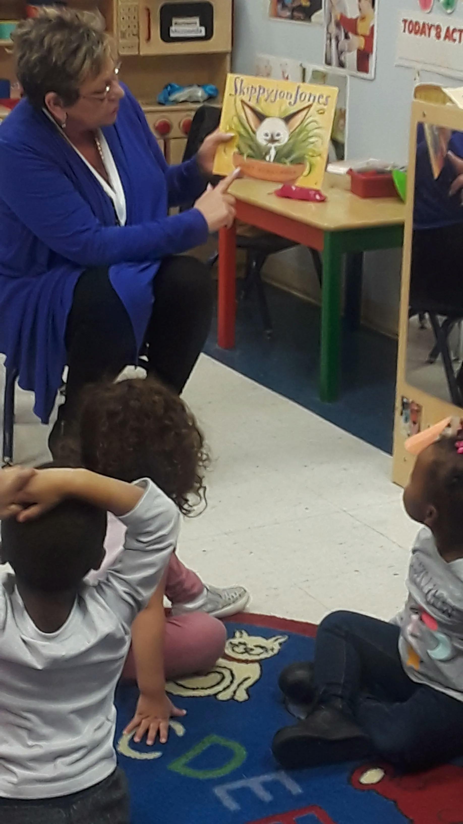 Person reading a book to children in a classroom