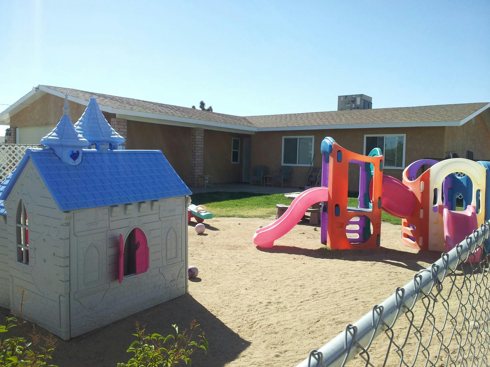 Playground with a playhouse and colorful slides in a sandy area