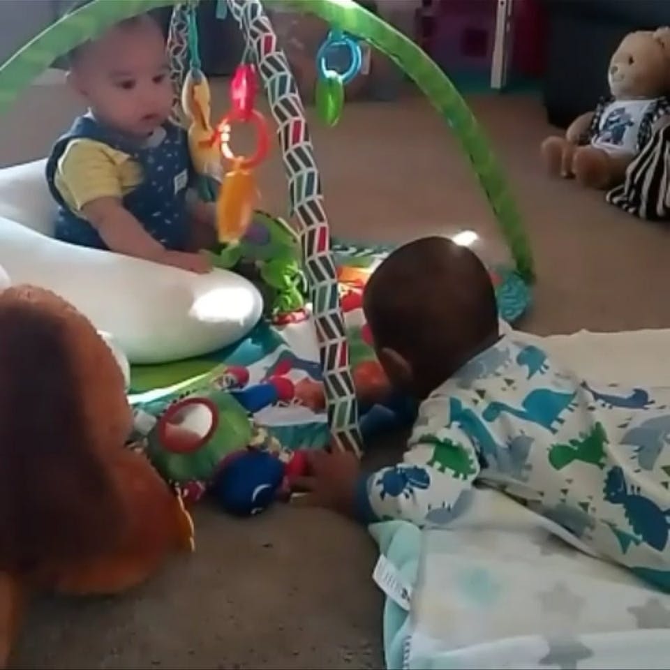 Two children playing with toys on a mat
