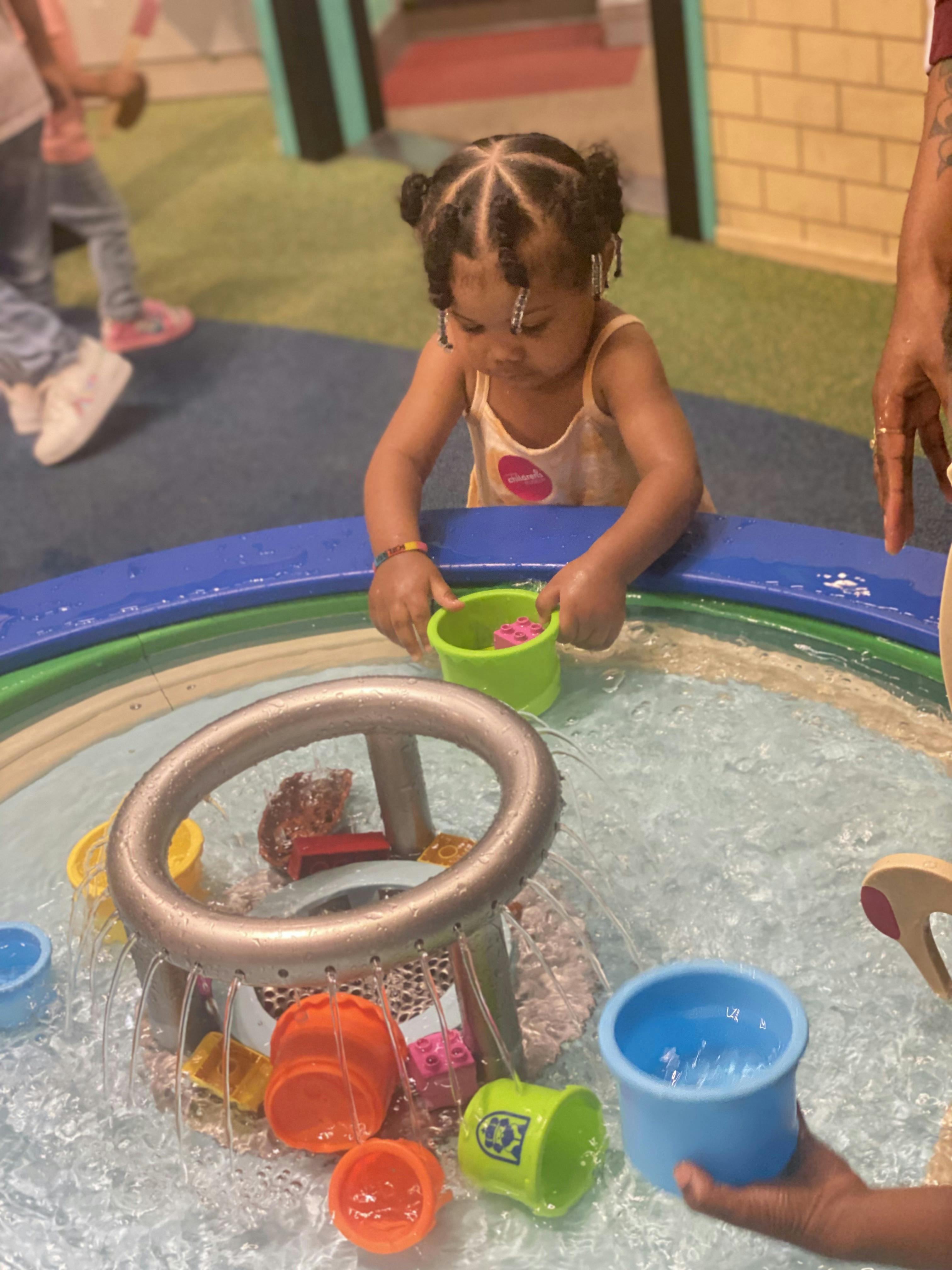 Child playing with toys in a water table at a children's museum