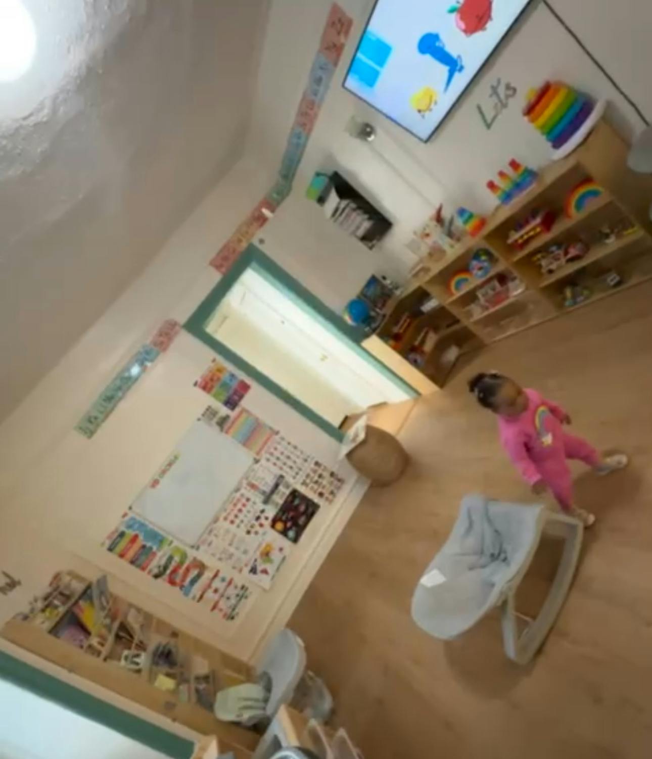 Child in pink clothing standing in a classroom