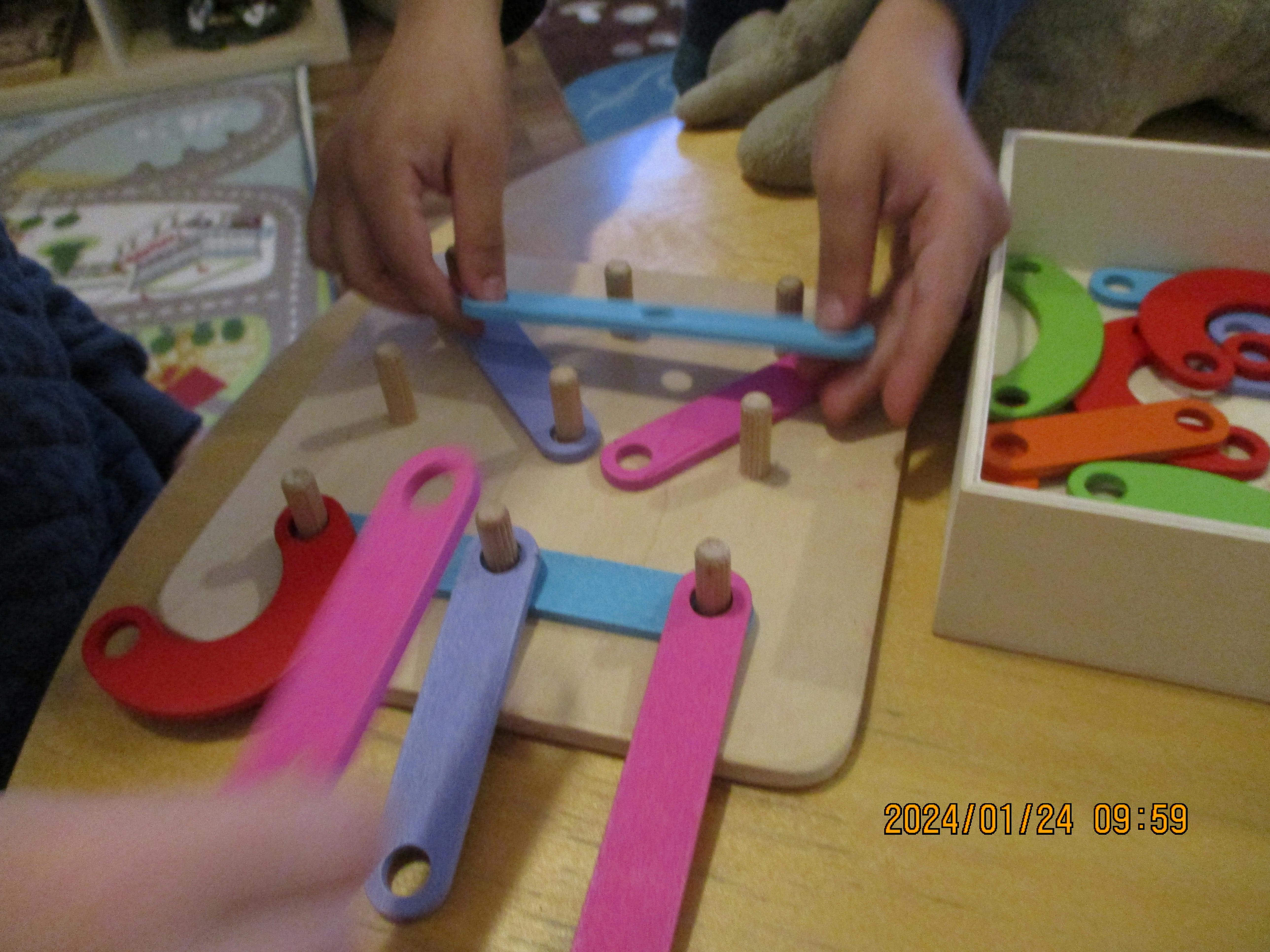 Person playing with a wooden pegboard and colorful linking pieces