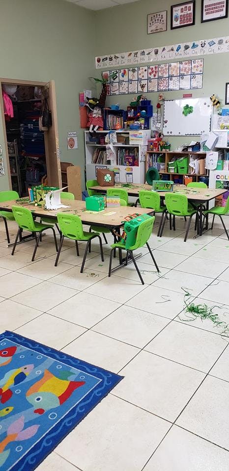 Classroom with small tables and green chairs, colorful rug on the floor