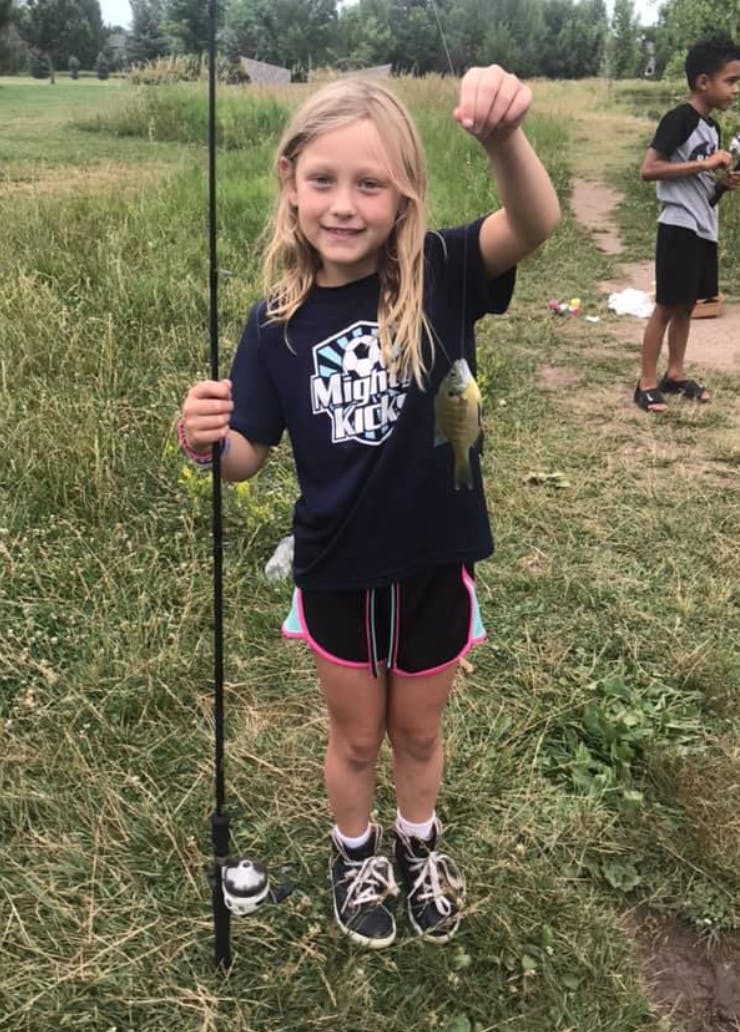 Child holding a fishing rod and a small fish