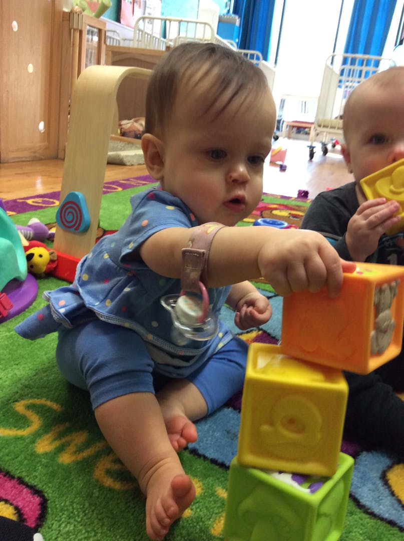 Child playing with stacking blocks on a colorful rug