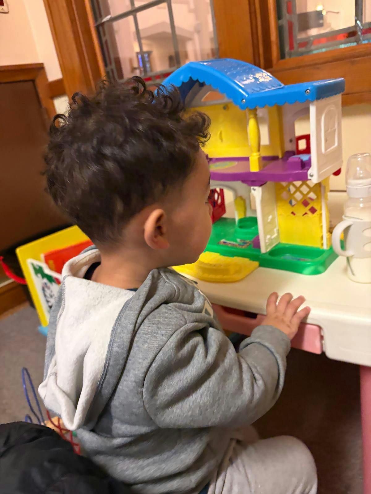 Child playing with a toy house on a table