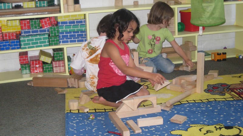 Children playing with wooden blocks on a rug