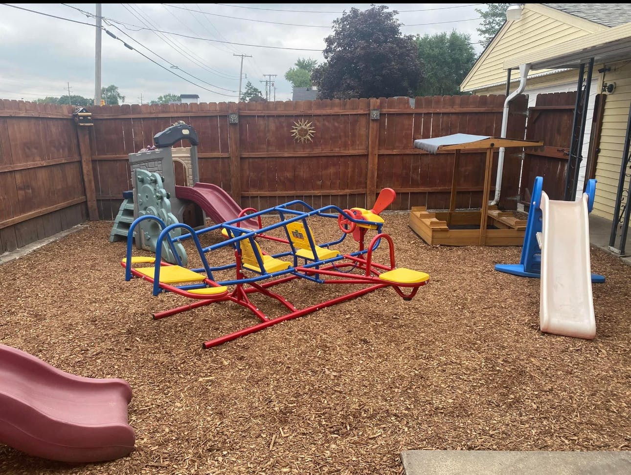Playground with a red and yellow seesaw, slides, and a sandbox