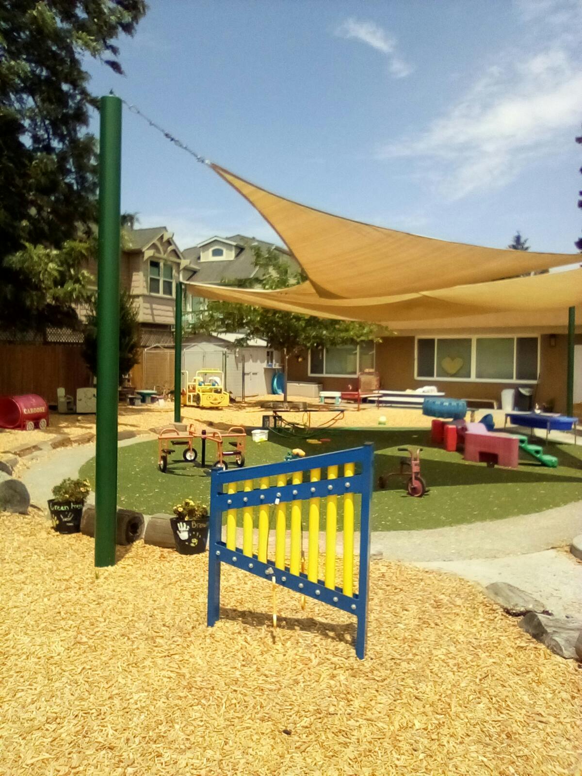 Outdoor playground with shade sails, artificial turf, and play equipment
