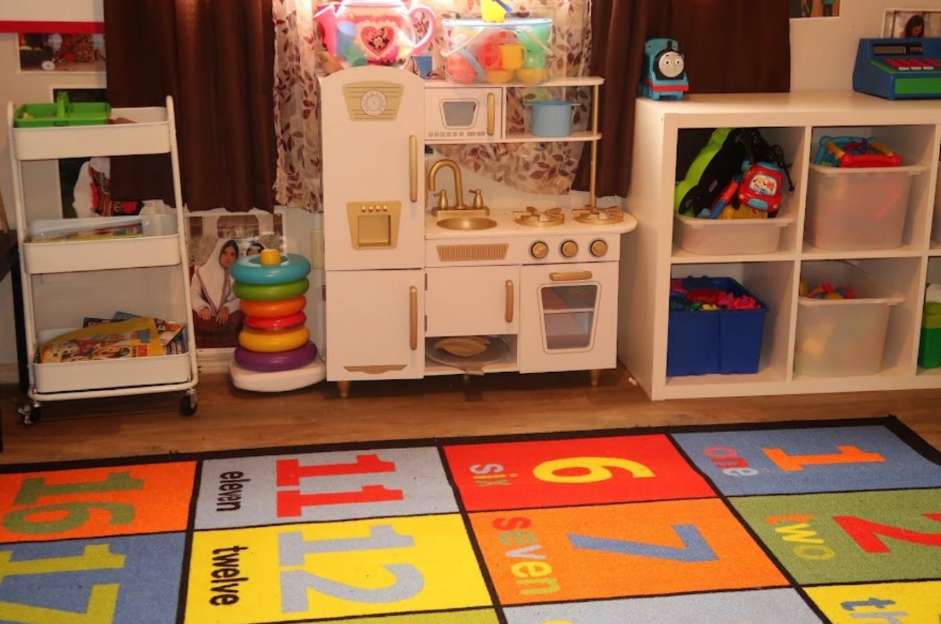 Playroom with toy kitchen, storage shelves, and a colorful number rug