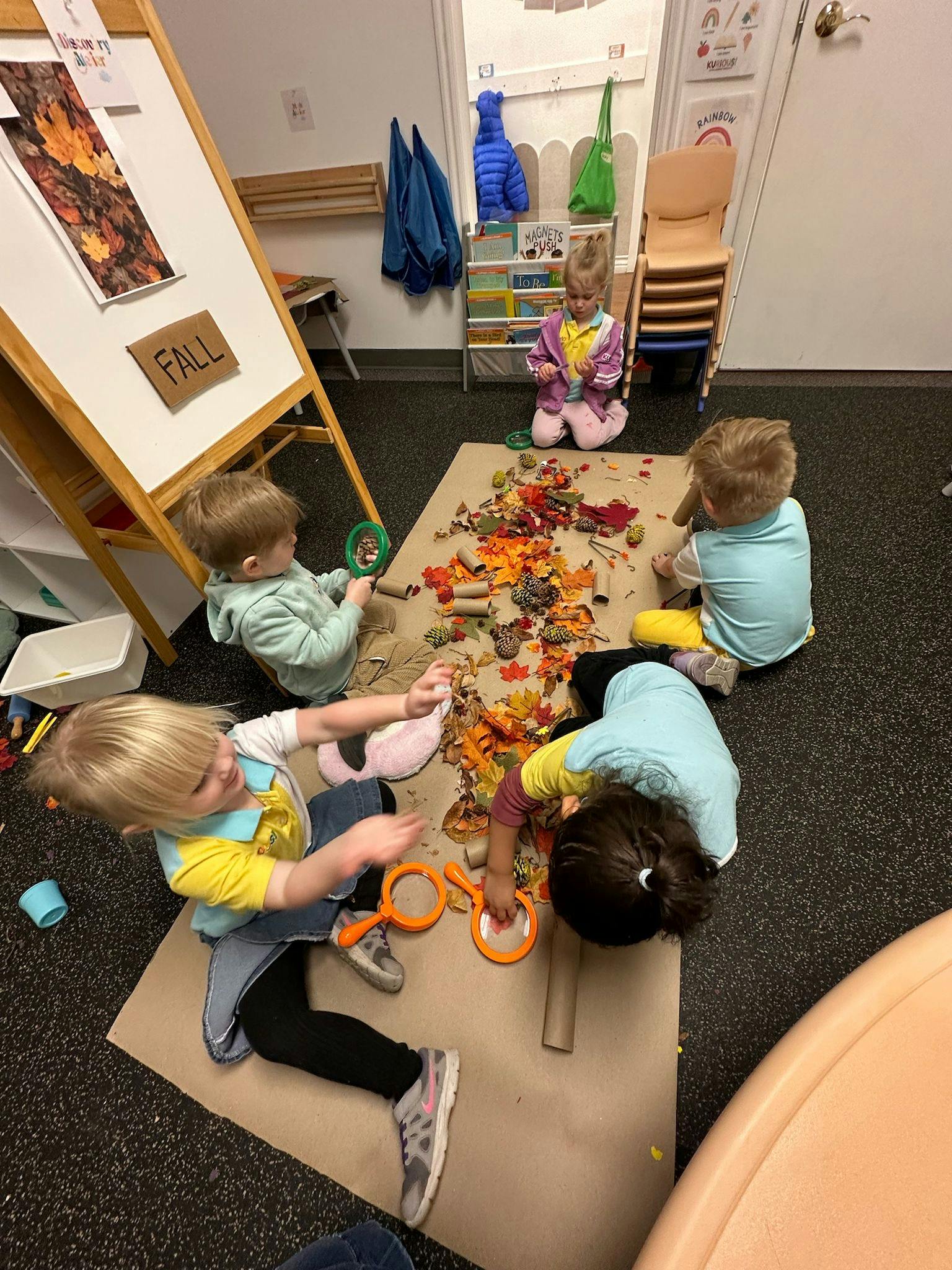 Children playing with fall-themed craft materials on the floor