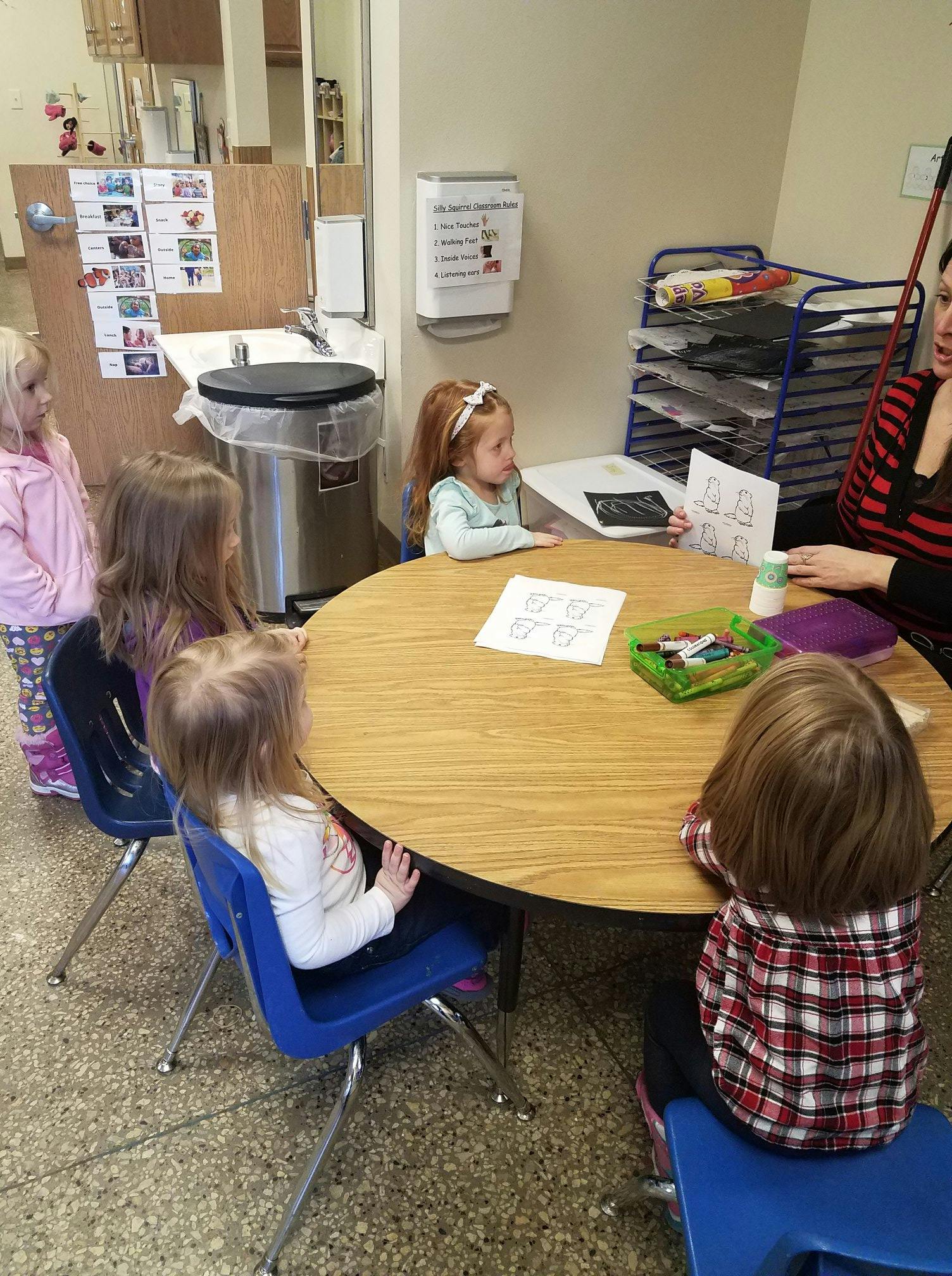 Adult and children sitting at a round table in a classroom