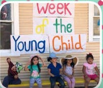 Four children sitting under a sign that reads "Week of the Young Child"